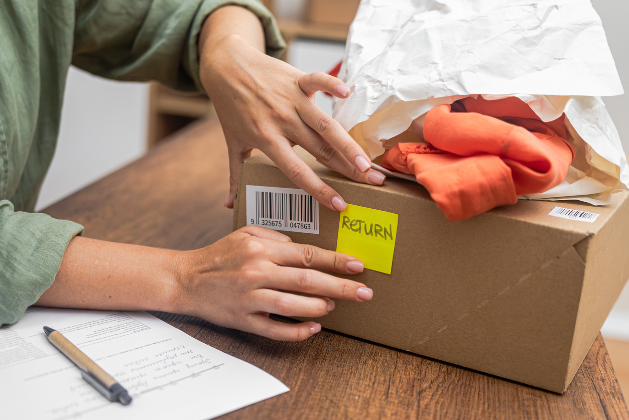 woman online shopper affixes a barcode sticker to a cardboard box, marking it for return and refund.